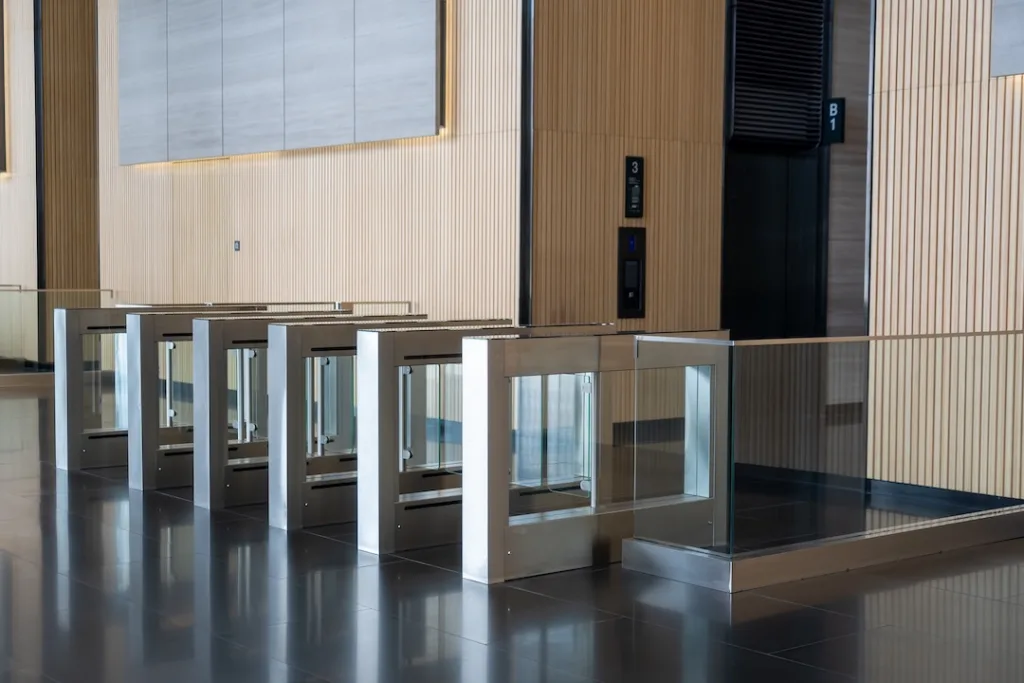Modern security turnstiles situated in sleek, contemporary lobby. The turnstiles are made of glass and metal, provide secure entry point in commercial building focused on both aesthetics and security