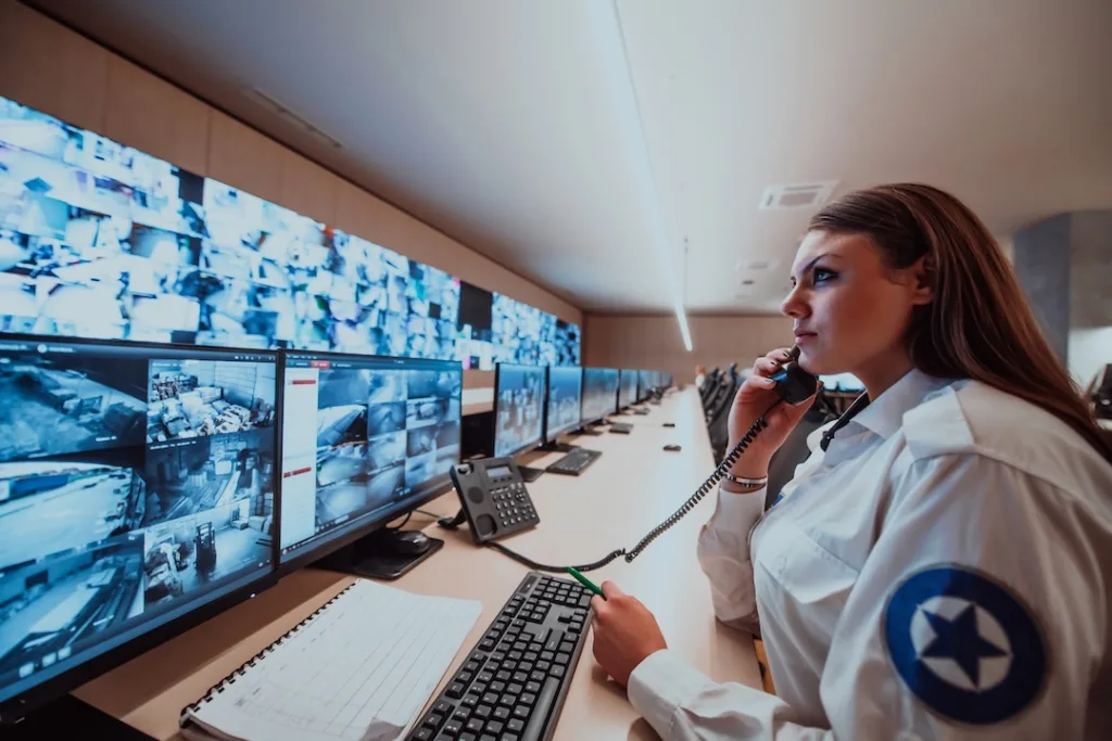Female security operator working in a data system control room offices Technical Operator Working at workstation with multiple displays, security guard working on multiple monitors